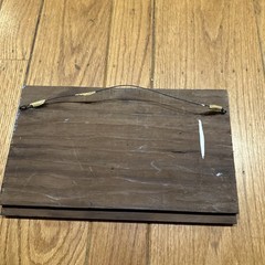 A rustic outhouse painting signed by Pat Flowers on a wood slice 12×7-1/2”